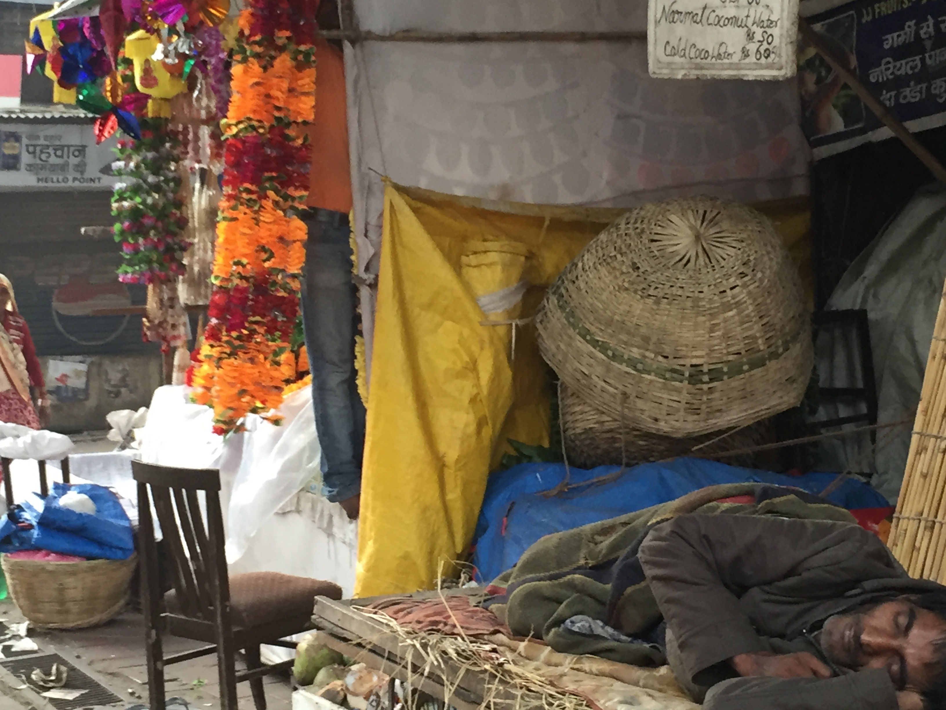 Coconut water vendor asleep in Indian market.